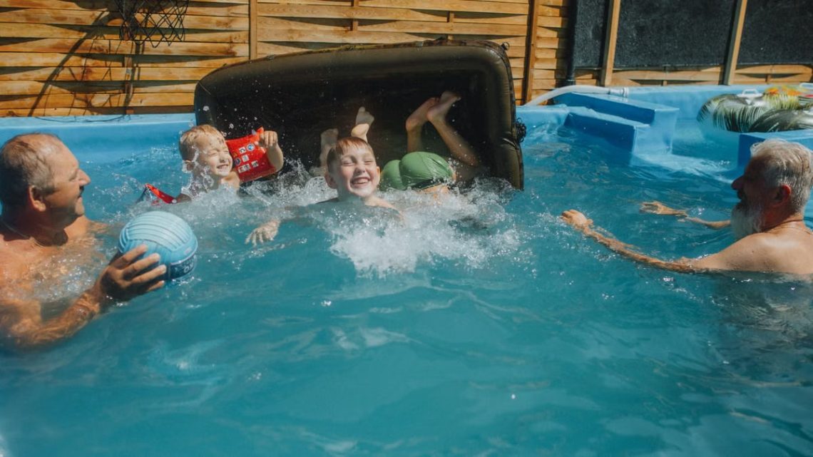 A joyful family enjoying a sunny day in a backyard swimming pool, playing and laughing.