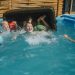 A joyful family enjoying a sunny day in a backyard swimming pool, playing and laughing.