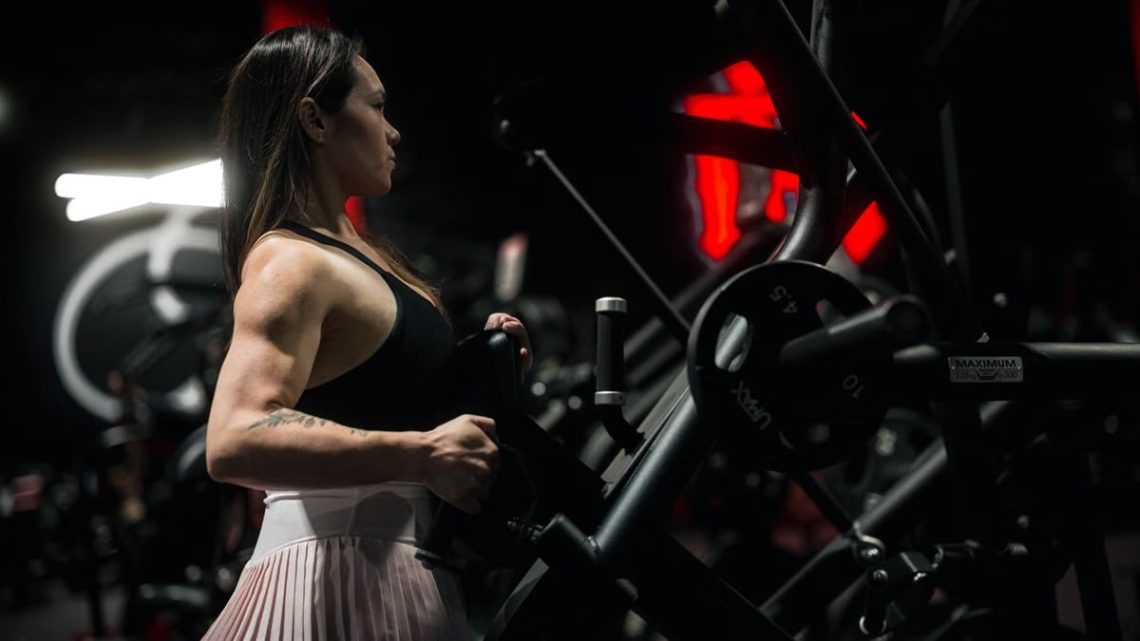 Focused woman engaging in a strength training session at the gym using robust fitness machinery.